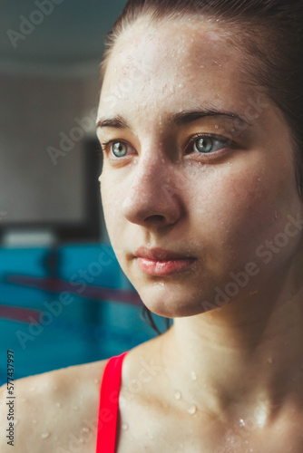 Young beautiful brunette girl on the background of the pool. Portrait of a girl near the side of the pool. Swimming, healthy lifestyle.