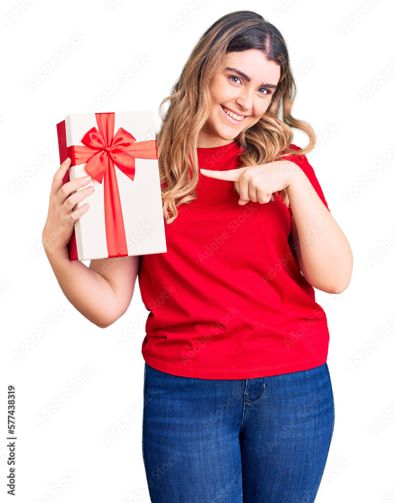 Young caucasian woman holding gift smiling happy pointing with hand and finger Young caucasian woman holding gift smiling happy pointing with hand and finger