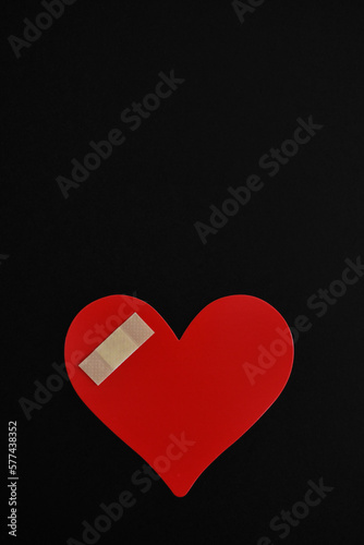 Corazón lastimado sobre fondo negro, espacio para texto en la parte superior. photo