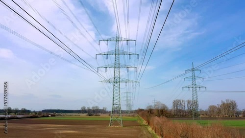 Low angle drone footage under Power Lines and High Voltage Electricity Pylons