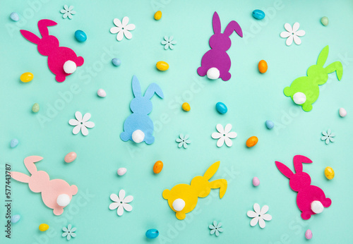 Colorful Bunnies, Easter Eggs with Sweets and Spring Flowers on Blue Background