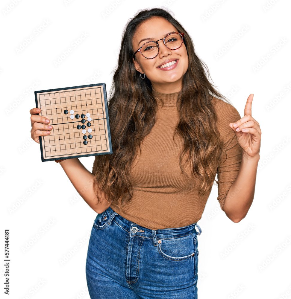 Young hispanic girl holding drauhgts surprised with an idea or question pointing finger with happy face, number one Young hispanic girl holding drauhgts surprised with an idea or question pointing finger with happy face, number one