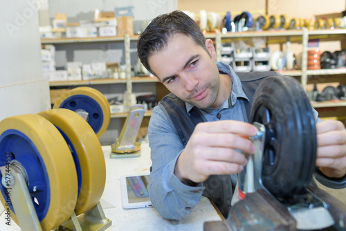 man fitting trolley wheel and tightening bolts