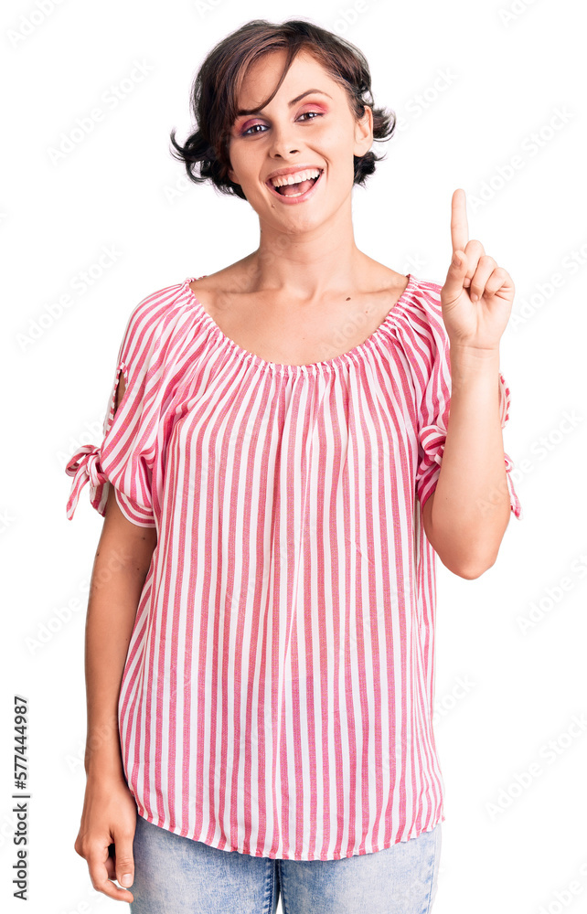 Beautiful young woman with short hair wearing casual summer clothes pointing finger up with successful idea. exited and happy. number one. Beautiful young woman with short hair wearing casual summer clothes pointing finger up with successful idea. exited and happy. number one.