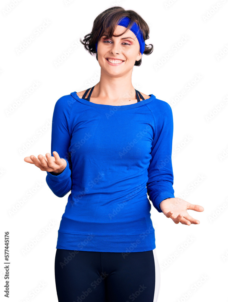 Beautiful young woman with short hair wearing training workout clothes smiling cheerful with open arms as friendly welcome, positive and confident greetings Beautiful young woman with short hair wearing training workout clothes smiling cheerful with open arms as friendly welcome, positive and confident greetings