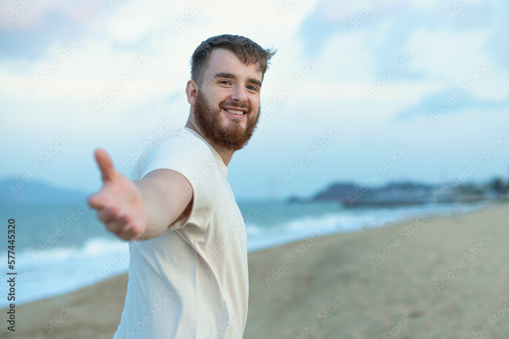 Portrait of happy young bearded guy, handsome man on the sea or ocean walking on beach enjoying good summer weather at vacation in tropical country Portrait of happy young bearded guy, handsome man on the sea or ocean walking on beach enjoying good summer weather at vacation in tropical country