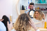 hairdresser shows style to customer using round mirror