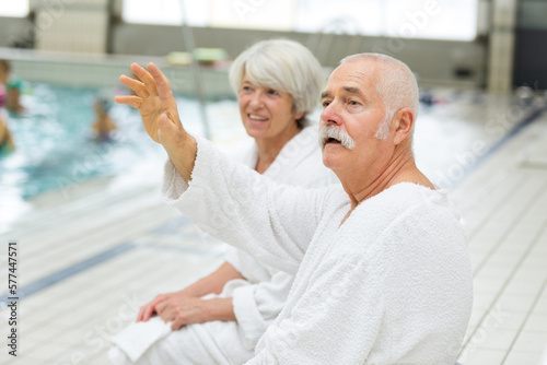 seniors wearing a bathrobe standing next to a swimming pool