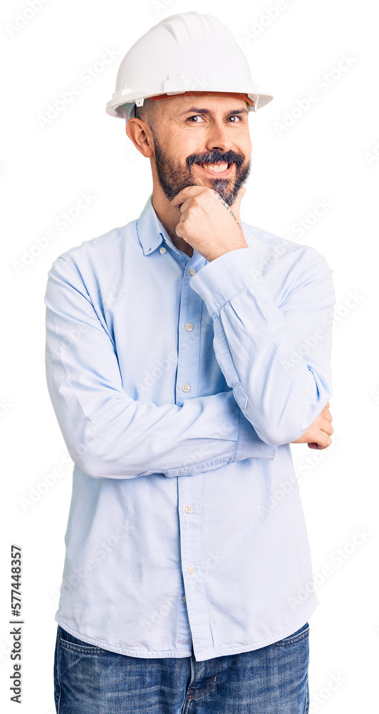 Young handsome man wearing architect hardhat looking confident at the camera smiling with crossed arms and hand raised on chin. thinking positive. Young handsome man wearing architect hardhat looking confident at the camera smiling with crossed arms and hand raised on chin. thinking positive.