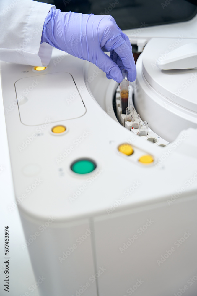 Laboratory assistant removes a test tube with a biomaterial sample Laboratory assistant removes a test tube with a biomaterial sample