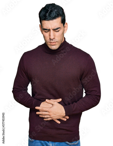 Handsome hispanic man wearing casual turtleneck sweater with hand on stomach because indigestion, painful illness feeling unwell. ache concept.