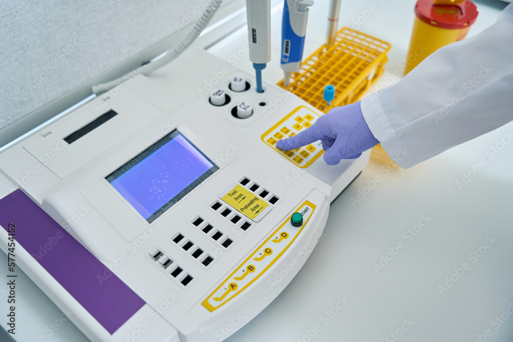 Top view of employee laboratory presses button coagulometer Top view of employee laboratory presses button coagulometer