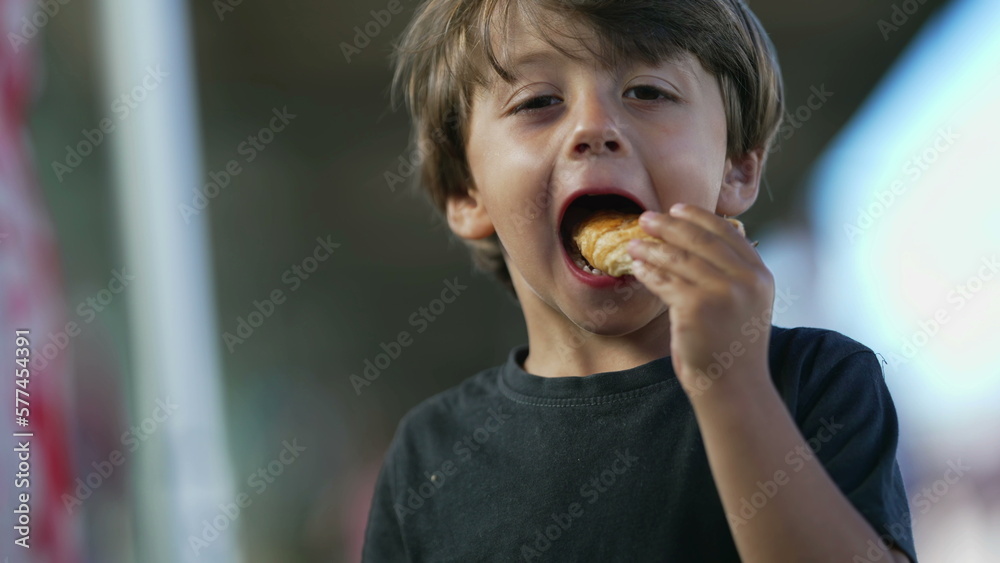 One cute small boy eating piece of bread outside. Child eats snack One cute small boy eating piece of bread outside. Child eats snack