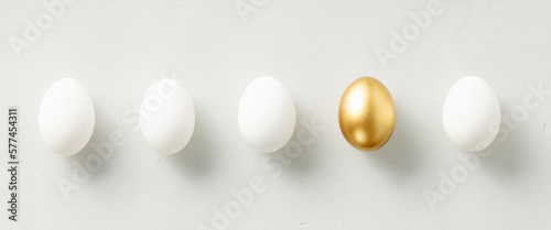 Fotografija White chicken eggs with one golden egg flat lay top view banner