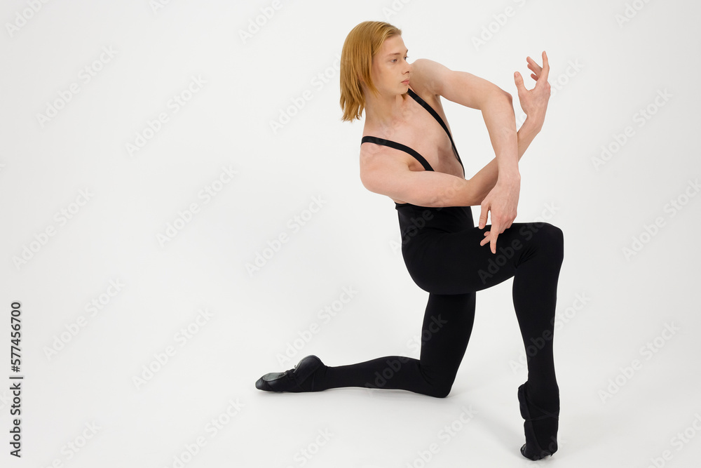 Obraz premium Young Athletic professional ballet dancer with a bare torso and black dance tights in a perfect shape performing over the white background.