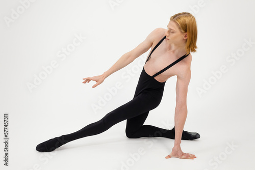 Young Athletic professional ballet dancer with a bare torso and black dance tights in a perfect shape performing over the white background.