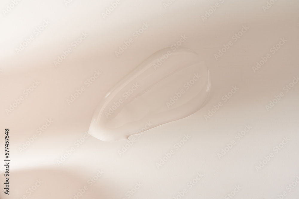 A smear of cosmetic cream with shadows on the sun. A white creamy drop of skin care cream. Fresh, smooth brushstroke on a light grey background with space to copy. Mockup for design.High quality photo