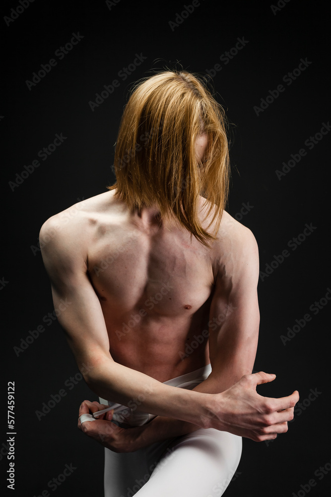 Young athletic professional ballet dancer with a bare torso and white dance tights is in perfect shape, performing and posing over a black background. Young athletic professional ballet dancer with a bare torso and white dance tights is in perfect shape, performing and posing over a black background.
