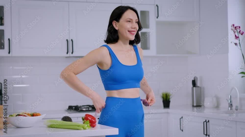 Slim athletic brunette woman measures her waist, slimming, healthy eating Slim athletic brunette woman measures her waist, slimming, healthy eating