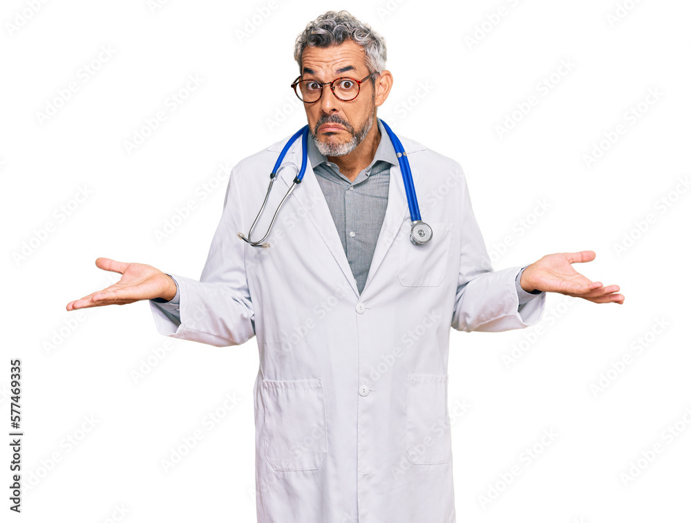 Middle age grey-haired man wearing doctor uniform and stethoscope clueless and confused expression with arms and hands raised. doubt concept. Middle age grey-haired man wearing doctor uniform and stethoscope clueless and confused expression with arms and hands raised. doubt concept.