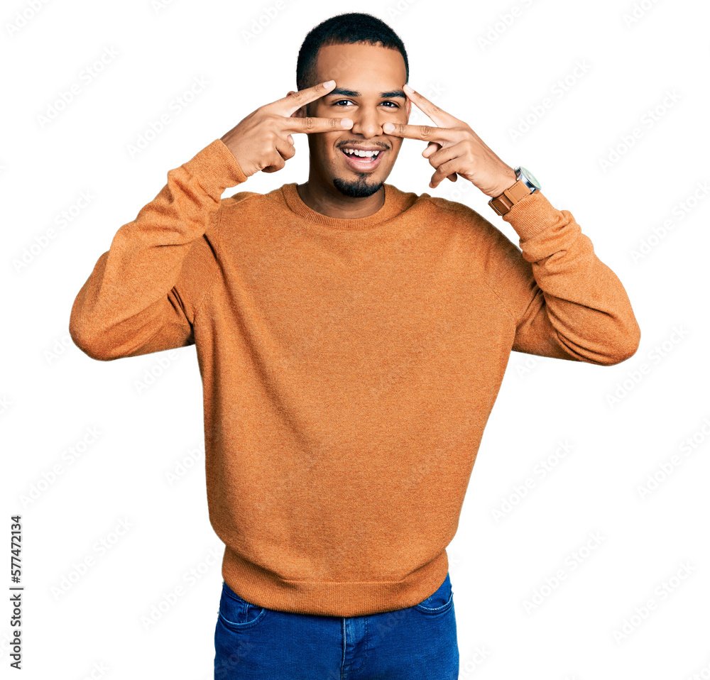 Young african american man wearing casual clothes doing peace symbol with fingers over face, smiling cheerful showing victory Young african american man wearing casual clothes doing peace symbol with fingers over face, smiling cheerful showing victory
