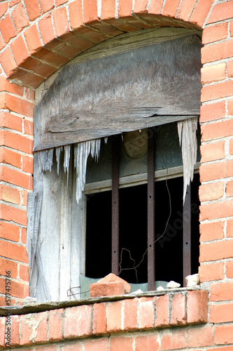 Broken barred window in abandoned brick building. 
