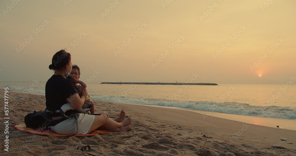 happy Asian person multi generation family sitting relax enjoy outdoor vacation holiday travel together on tropical ocean sea beach during sunset sunrise in summer nature, leisure carefree freedom