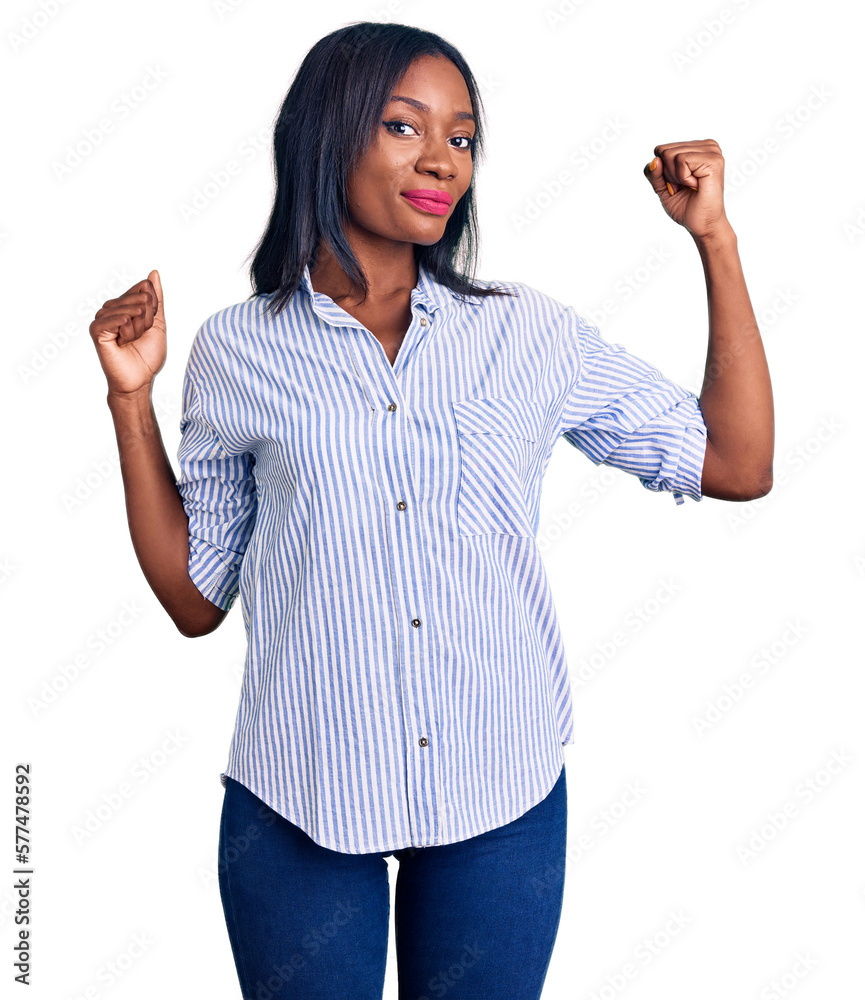 Obraz premium Young african american woman wearing casual clothes showing arms muscles smiling proud. fitness concept.