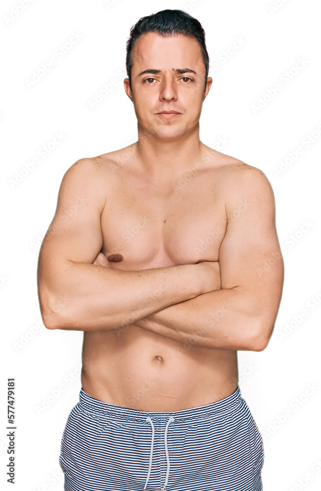Handsome young man wearing swimwear shirtless skeptic and nervous, disapproving expression on face with crossed arms. negative person. Handsome young man wearing swimwear shirtless skeptic and nervous, disapproving expression on face with crossed arms. negative person.