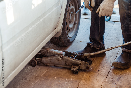 An old jack raises a wheel close-up,in a workshop for cars