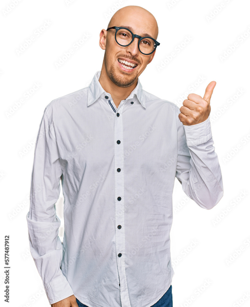 Bald man with beard wearing business shirt and glasses smiling with happy face looking and pointing to the side with thumb up.