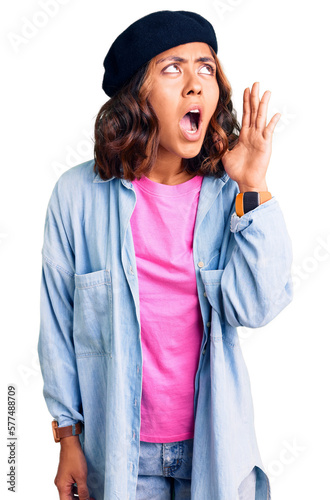 Young beautiful mixed race woman wearing french look with beret shouting and screaming loud to side with hand on mouth. communication concept.