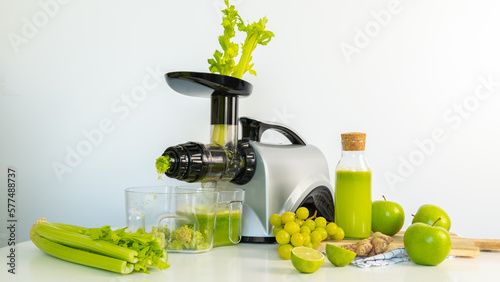 Squeeze the green juice of celery and apples on an auger juicer in the kitchen 