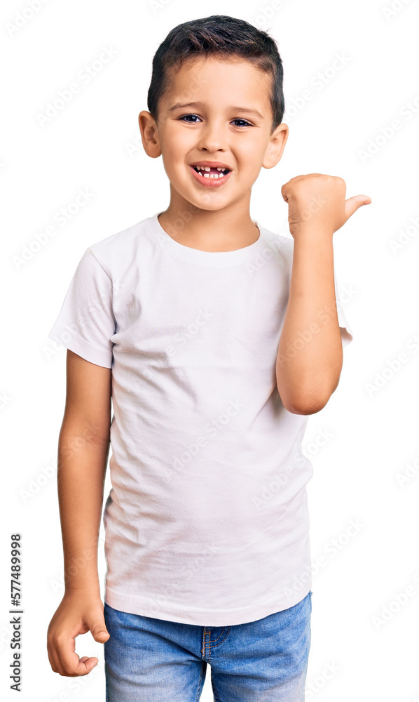 Little cute boy kid wearing casual white tshirt smiling with happy face looking and pointing to the side with thumb up. Little cute boy kid wearing casual white tshirt smiling with happy face looking and pointing to the side with thumb up.