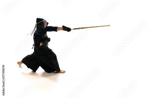 Man, professional kendo athlete in uniform with helmet training with bamboo shinai sword against white studio background. Concept of martial arts, sport, Japanese culture, action and motion