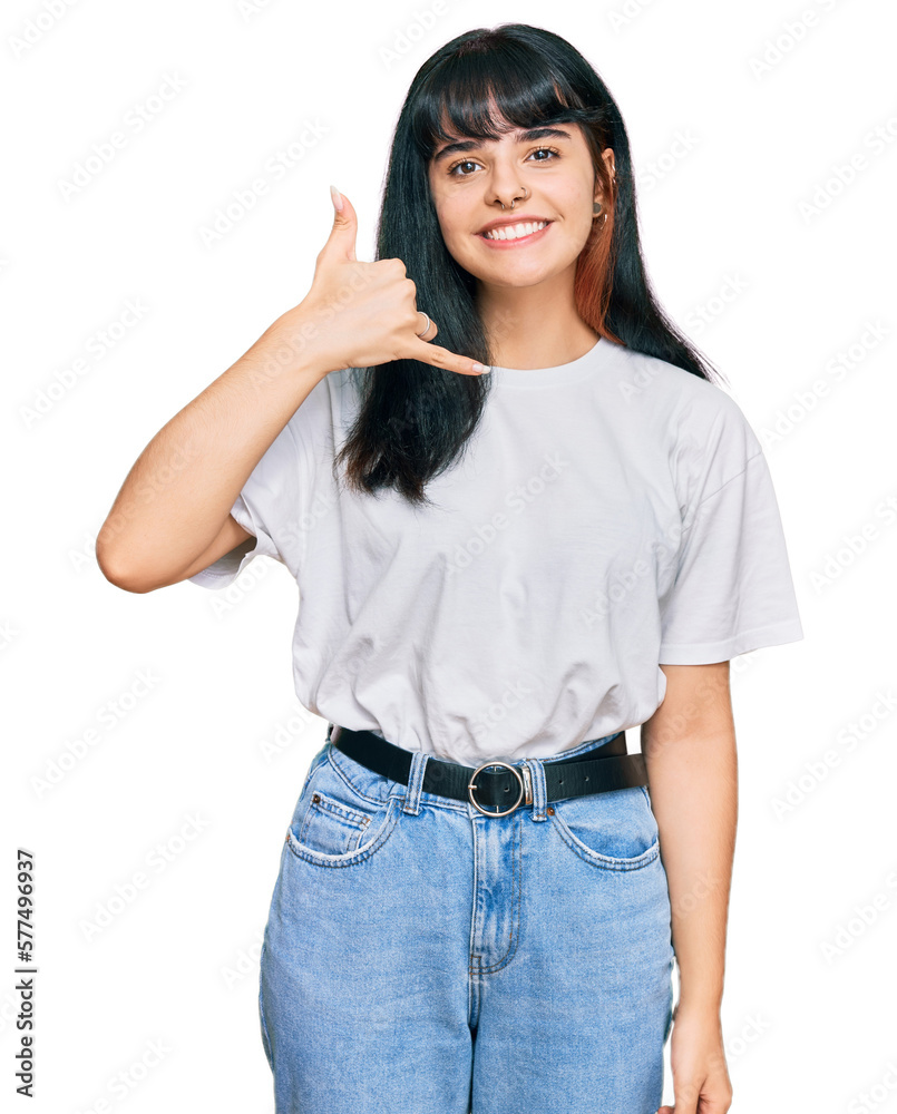 Young hispanic girl wearing casual clothes smiling doing phone gesture with hand and fingers like talking on the telephone. communicating concepts. Young hispanic girl wearing casual clothes smiling doing phone gesture with hand and fingers like talking on the telephone. communicating concepts.