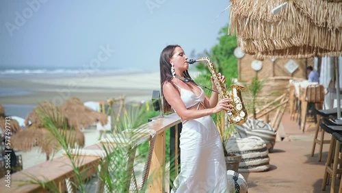 A beautiful young woman of beautiful appearance plays a golden saxophone.
