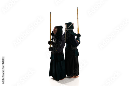 Top view. Back to back. Two men, professional kendo athletes in uniform posing shinai sword against white studio background. Concept of martial arts, sport, Japanese culture, action and motion