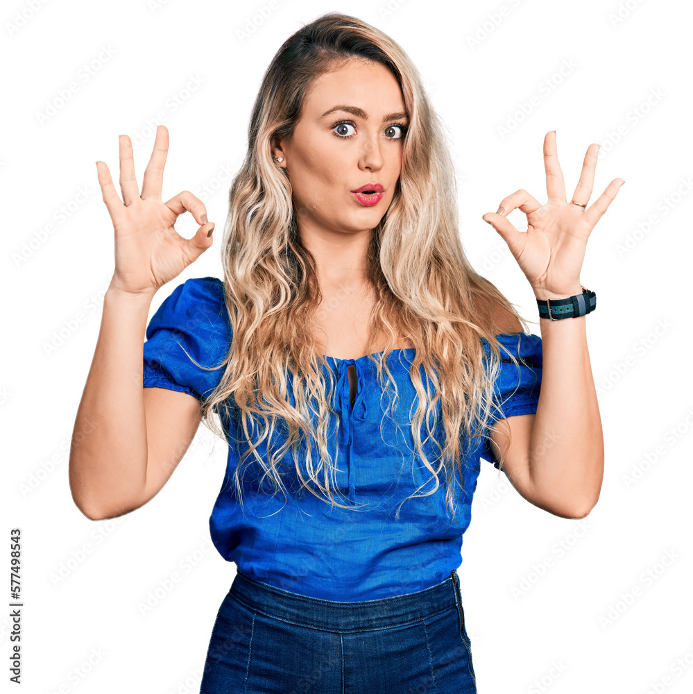 Fototapeta premium Young blonde woman wearing casual clothes looking surprised and shocked doing ok approval symbol with fingers. crazy expression