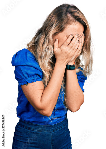 Young blonde woman wearing casual clothes with sad expression covering face with hands while crying. depression concept.