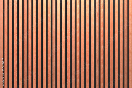 A wall of wooden slats in the color of natural wood with a pattern of wall panels in the background