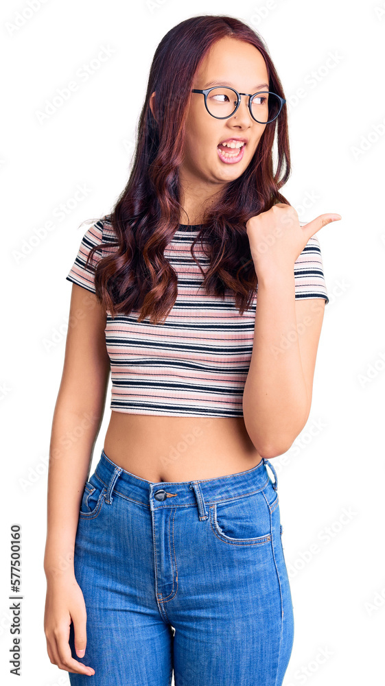 Young beautiful chinese girl wearing casual clothes smiling with happy face looking and pointing to the side with thumb up. Young beautiful chinese girl wearing casual clothes smiling with happy face looking and pointing to the side with thumb up.