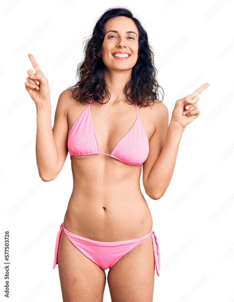 Young beautiful hispanic woman wearing bikini smiling confident pointing with fingers to different directions. copy space for advertisement Young beautiful hispanic woman wearing bikini smiling confident pointing with fingers to different directions. copy space for advertisement