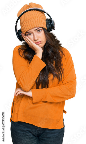 Beautiful brunette young woman listening to music using headphones thinking looking tired and bored with depression problems with crossed arms. © Krakenimages.com