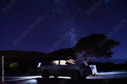 Milky way over a tent located on the roof of a pickup car in the Namib desert in Namibia. Night photo with many stars.