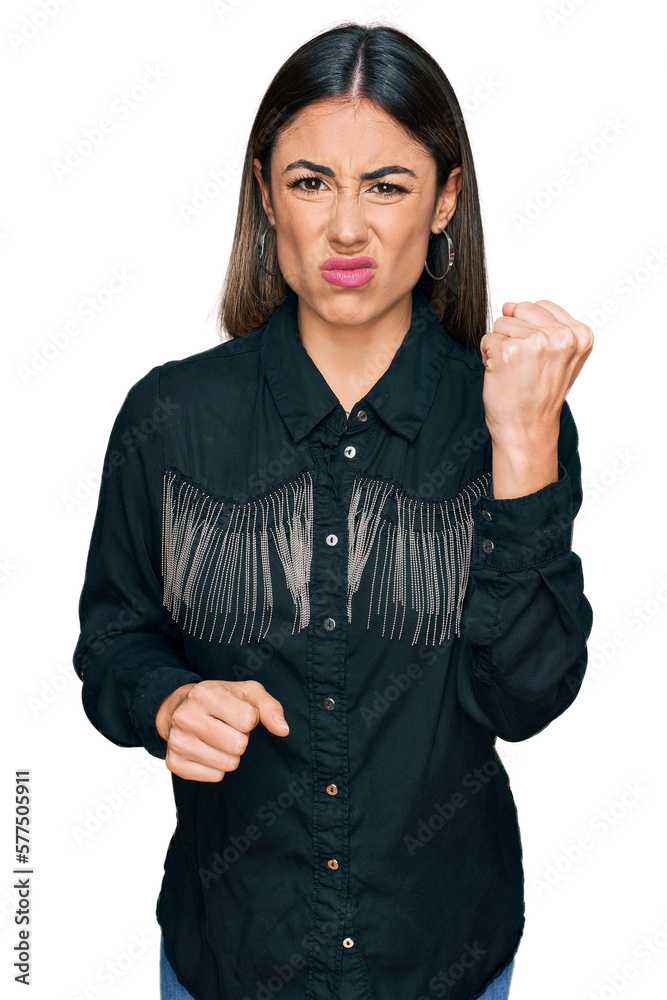 Young hispanic woman wearing casual clothes angry and mad raising fist frustrated and furious while shouting with anger. rage and aggressive concept. Young hispanic woman wearing casual clothes angry and mad raising fist frustrated and furious while shouting with anger. rage and aggressive concept.