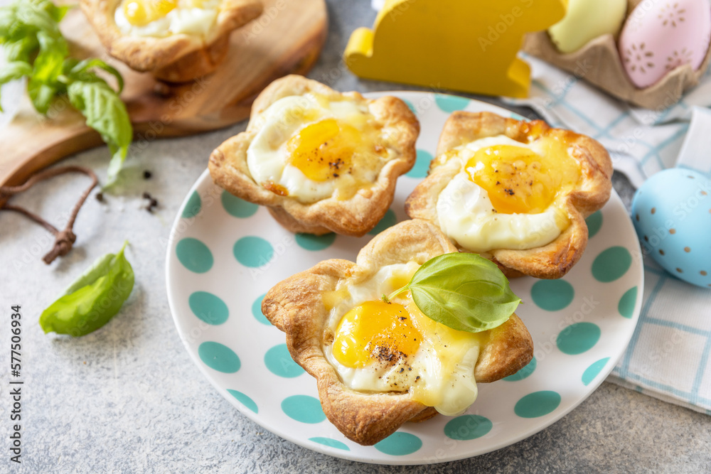 Easter breakfast idea. Scrambled eggs in puff pastry with cheese and bacon on a stone background. Easter breakfast idea. Scrambled eggs in puff pastry with cheese and bacon on a stone background.