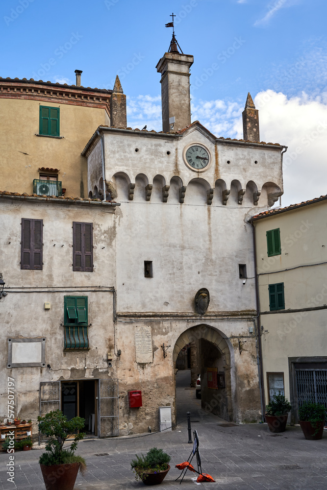 Cobblestone square with stone houses and city gate in Scansano