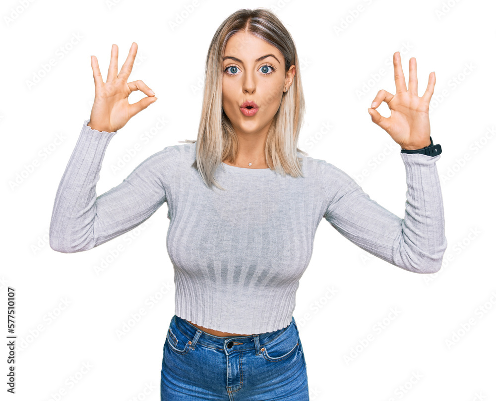 Beautiful blonde woman wearing casual clothes looking surprised and shocked doing ok approval symbol with fingers. crazy expression Beautiful blonde woman wearing casual clothes looking surprised and shocked doing ok approval symbol with fingers. crazy expression