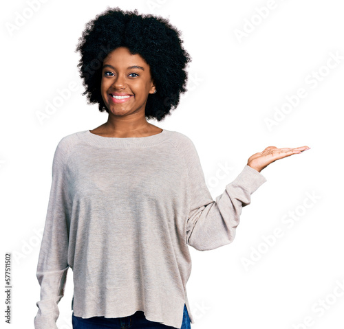 Young african american woman wearing casual clothes smiling cheerful presenting and pointing with palm of hand looking at the camera.